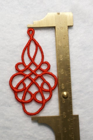 Lightweight Grace Embroidered Dangle Earrings in Red being measure in a brass calliper