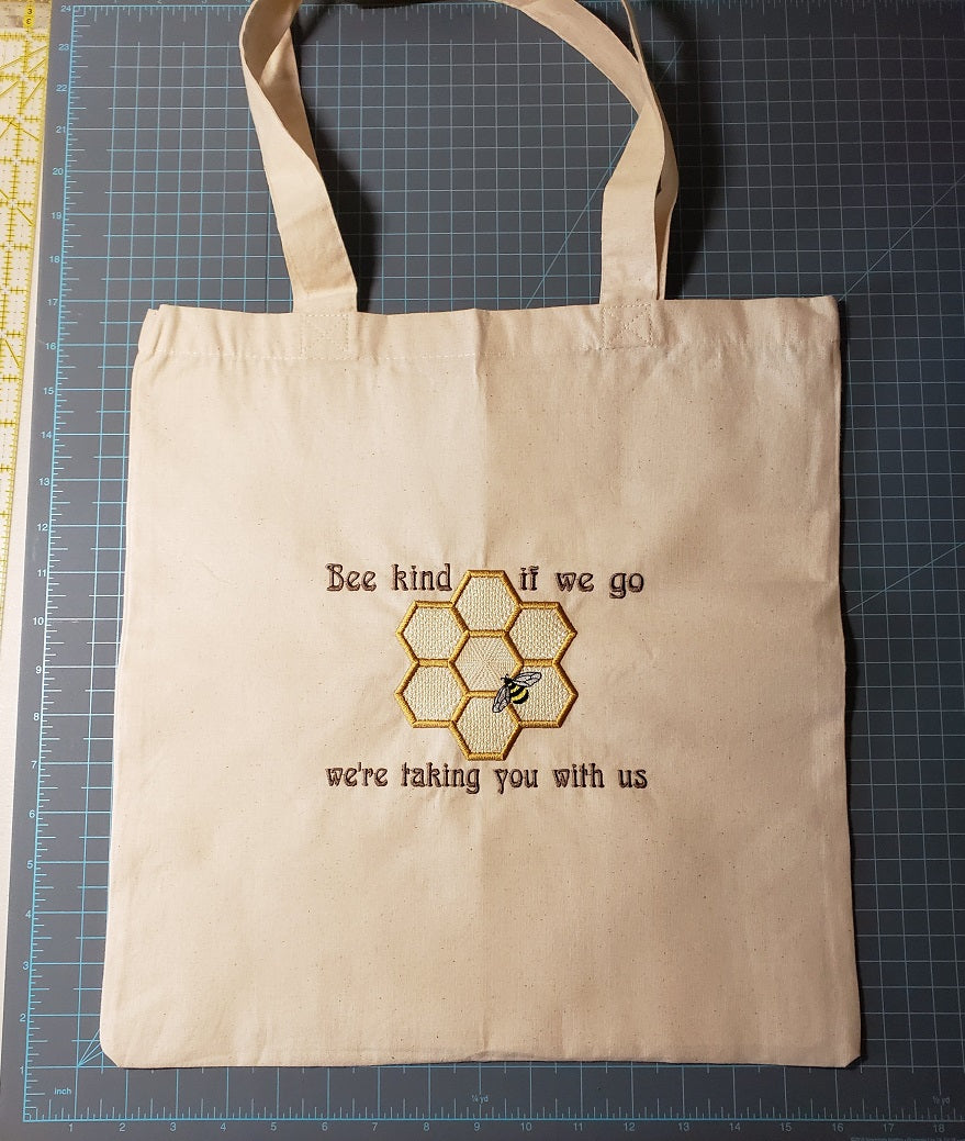 Natural colored cotton tote bag with a  Bee and honeycomb with the phrase Bee kind, if we go we're taking you with us