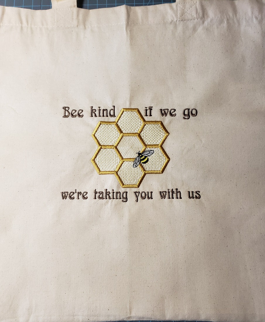 Natural colored cotton tote bag with a  Bee and honeycomb with the phrase Bee kind, if we go we're taking you with us