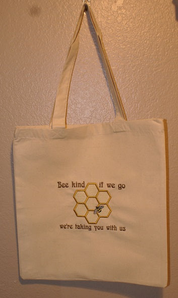 Natural colored cotton tote bag with a  Bee and honeycomb with the phrase Bee kind, if we go we're taking you with us.