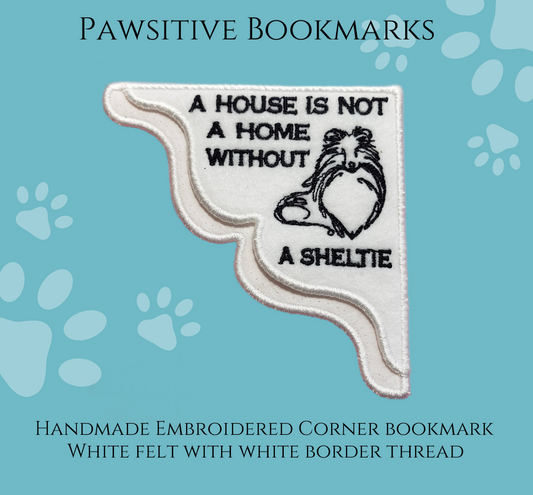 A White Felt Corner Bookmark with a black outline image of a Sheltie with the phrase “A house is not a home without a Sheltie”